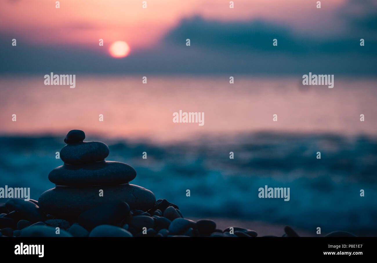 Piramide piegata Zen pietre ghiaia sul mare spiaggia al tramonto Foto Stock