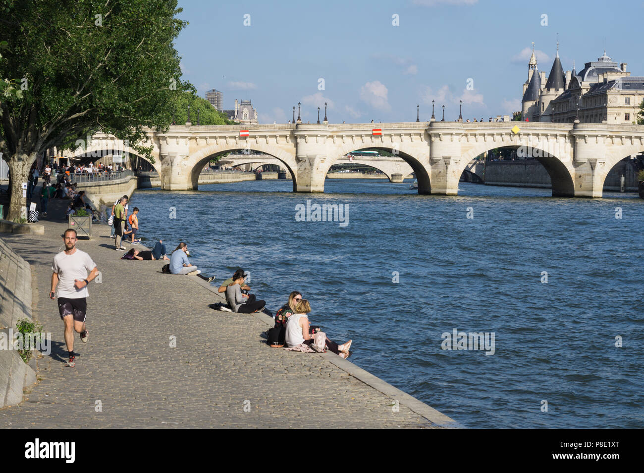 Persone rilassante sull'argine di destra del Fiume Senna con una vista al Pont Neuf ponte in Parigi, Francia. Foto Stock