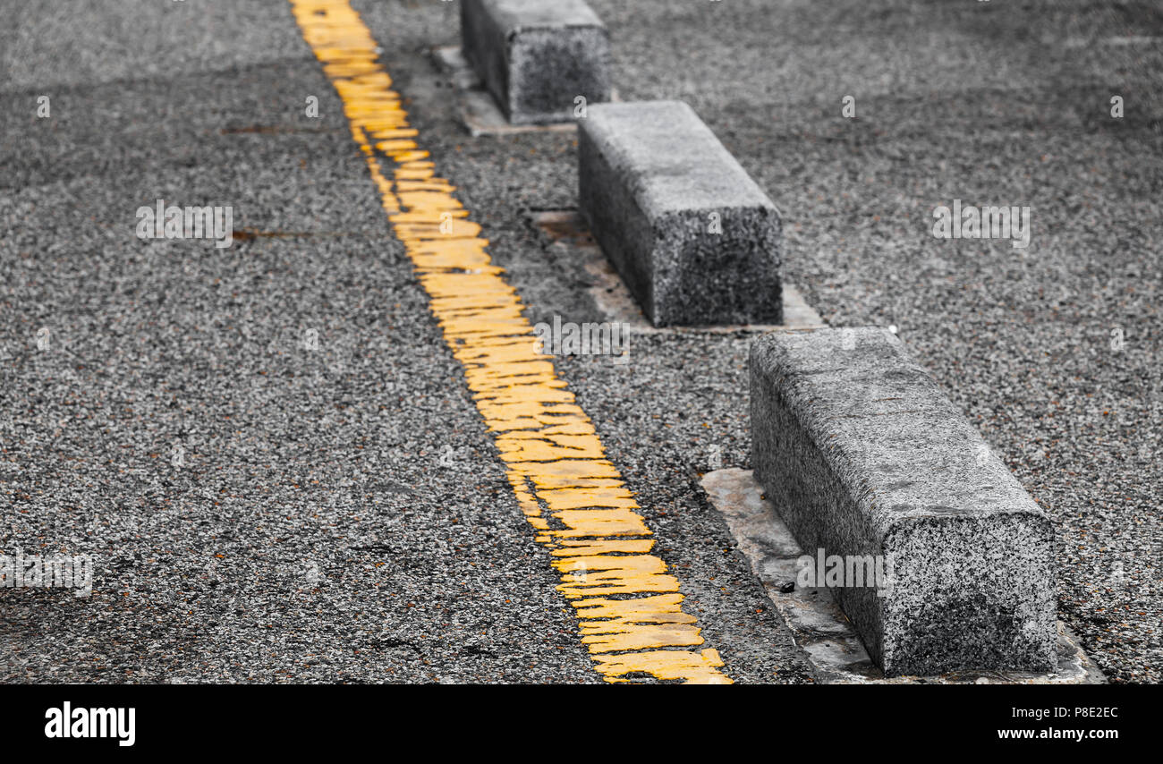 Calcestruzzo lato strada blocchi alle frontiere e giallo linea divisoria. Close-up foto con messa a fuoco selettiva Foto Stock