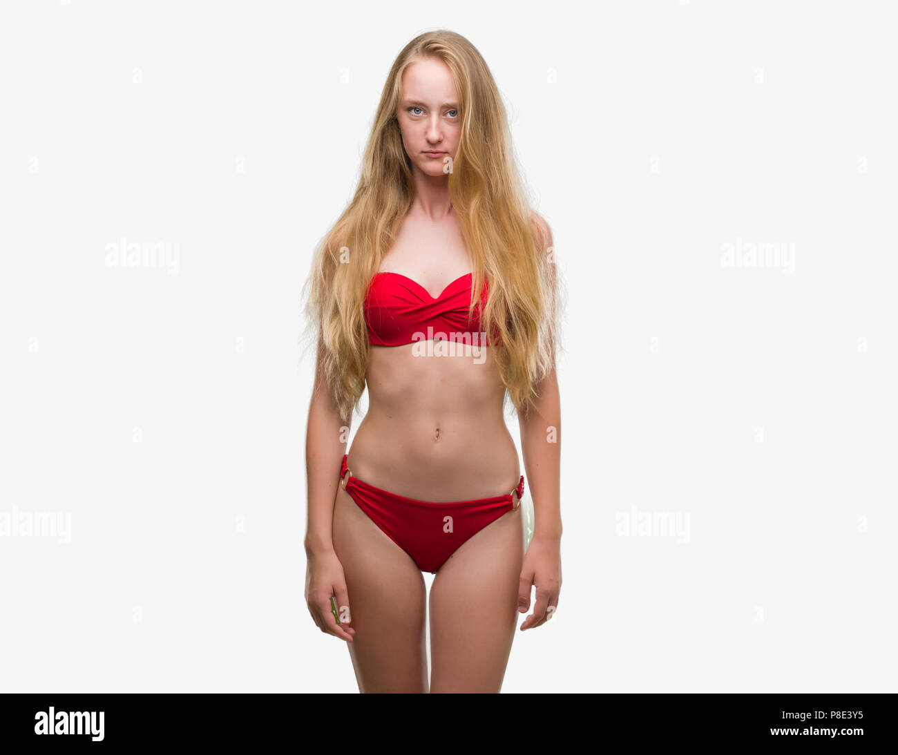 Adolescente bionda donna che indossa un bikini rosso scettico e nervoso, accigliata sconvolto a causa del problema. Persona negativa. Foto Stock