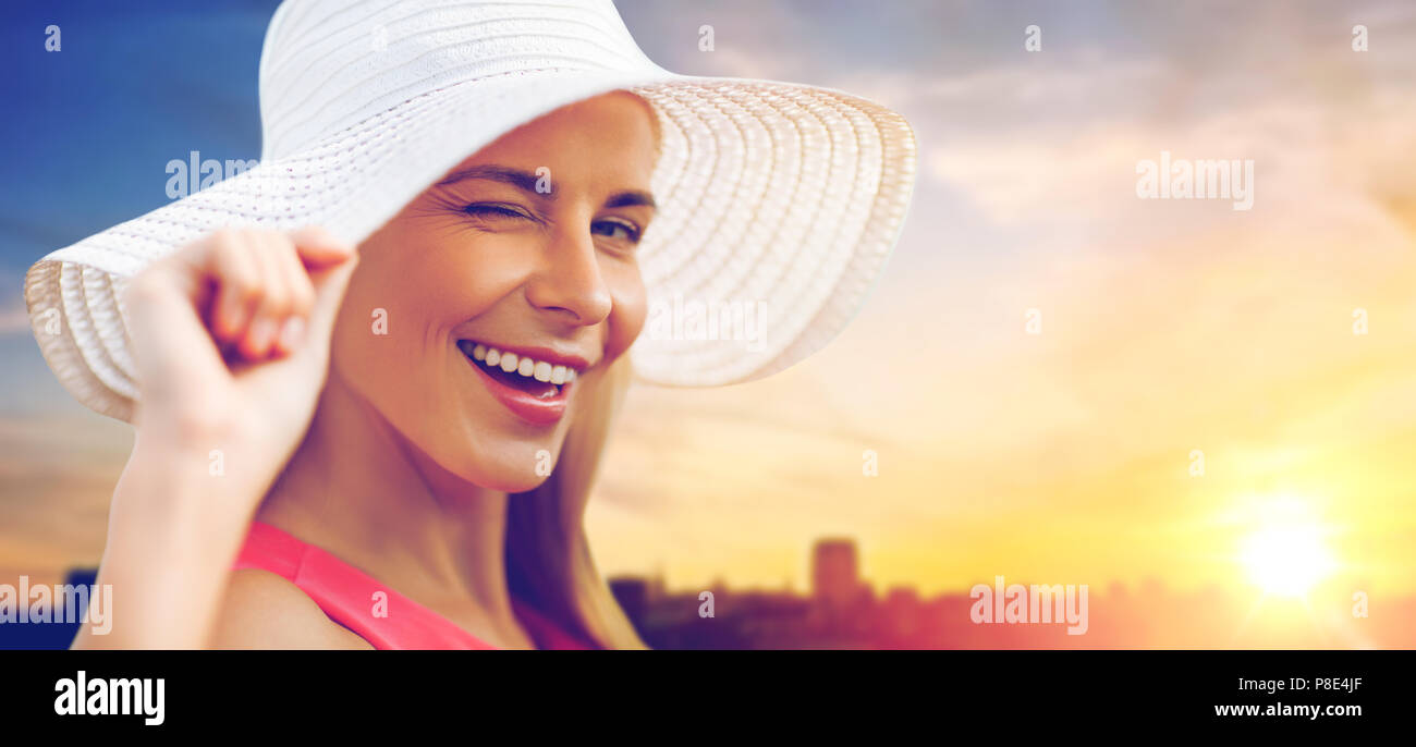Bella donna sorridente nel cappello per il sole oltre il tramonto Foto Stock