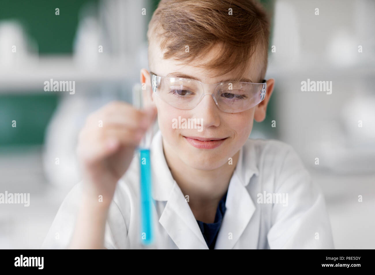 Ragazzo con tubo di prova che studia chimica a scuola Foto Stock