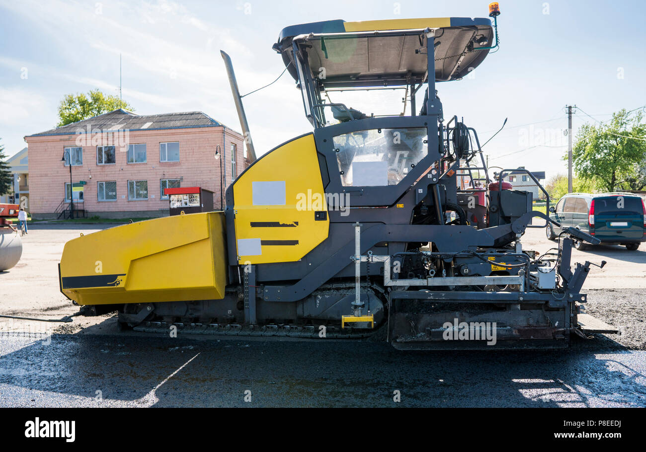 Lavoratore di asfalto operativo lastricatore macchina durante la costruzione di strade e lavori di riparazione. Un lastricatore finisher, asfalto di finitura o macchina di pavimentazione disporre uno strato di asfalto. Ripavimentazione Foto Stock