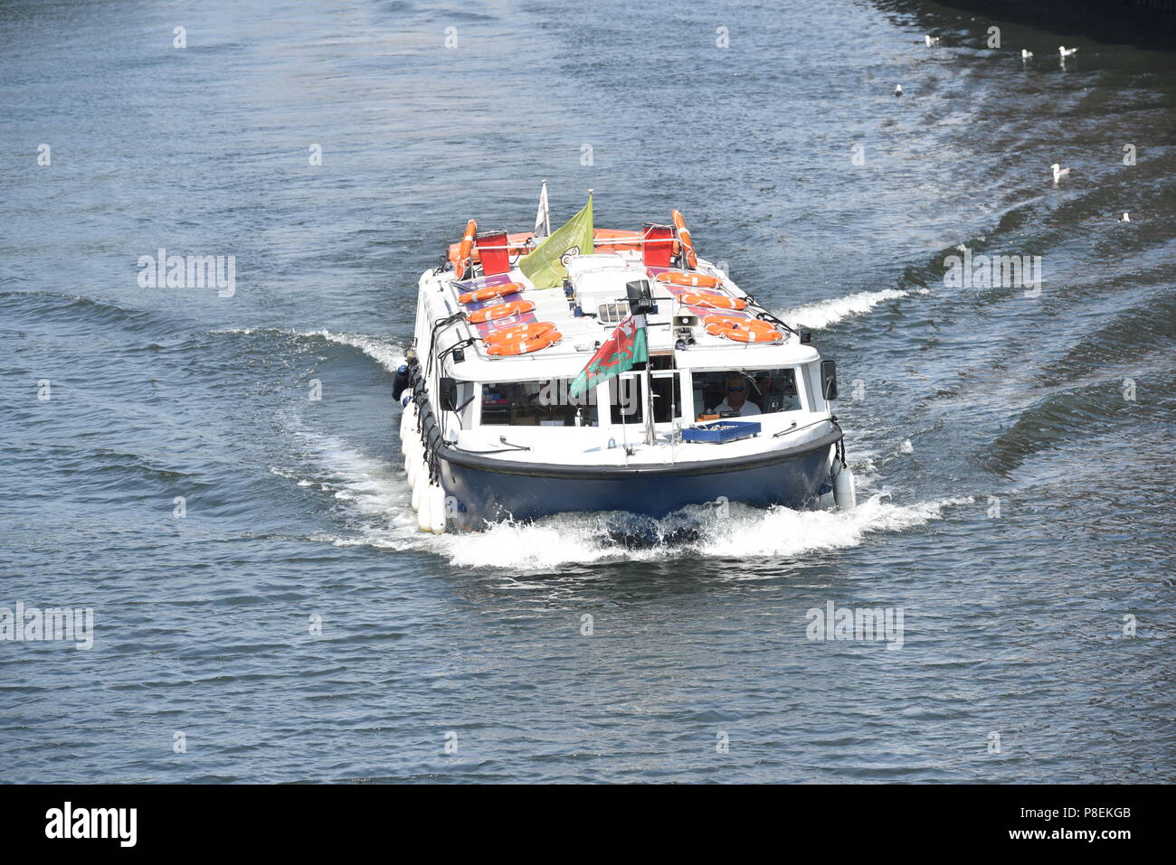 La figura mostra un autobus di acqua rendendo la sua strada giù per il fiume Taff, Cardiff, Galles del Sud, a fianco del Principato Stadium, Taffs Mead stop con Nextbike Foto Stock