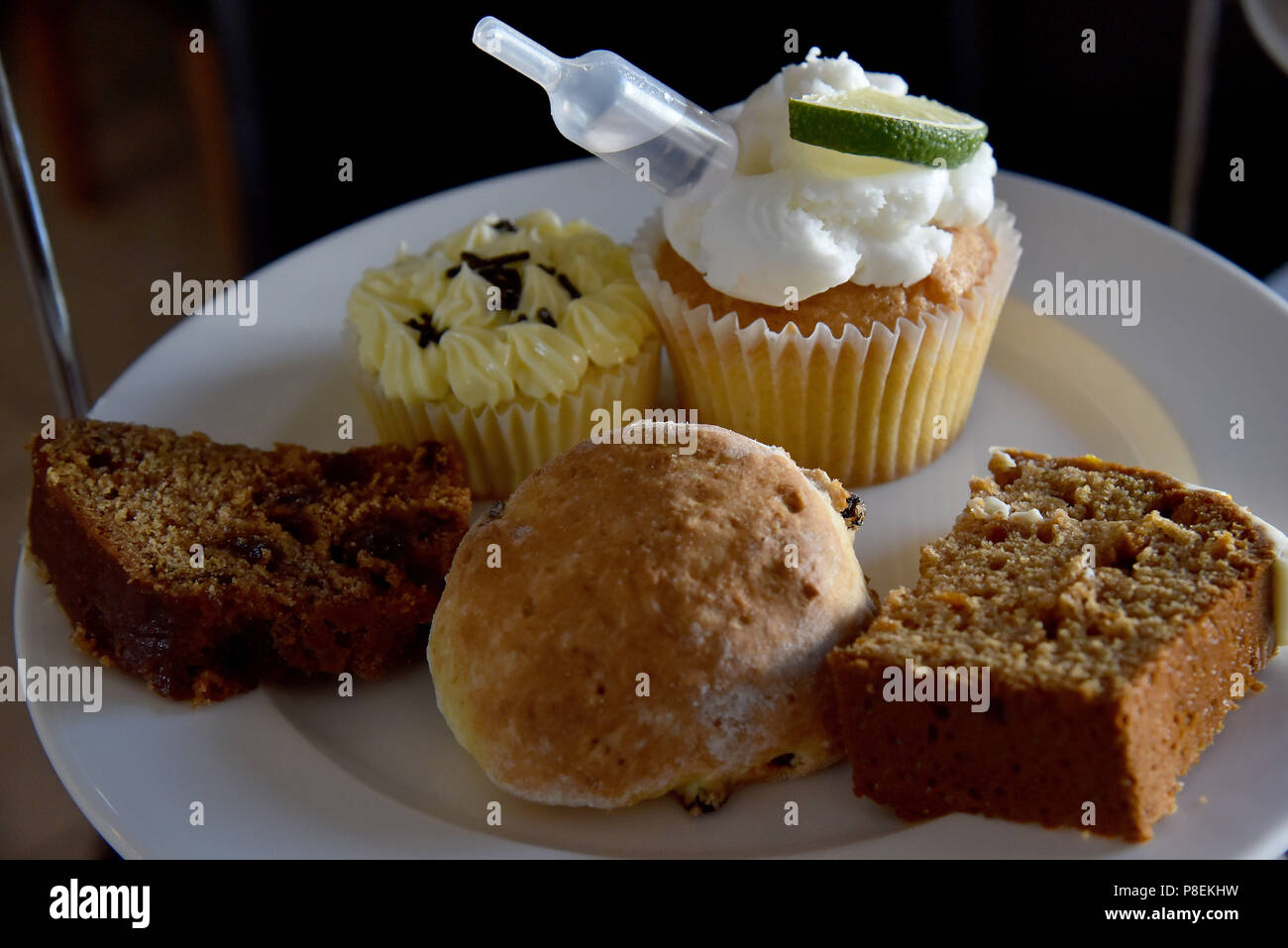La figura mostra una torta stand contenente pasticcini includente un cup cake, un cornetto, data e noce e una fetta di torta di caffè Foto Stock