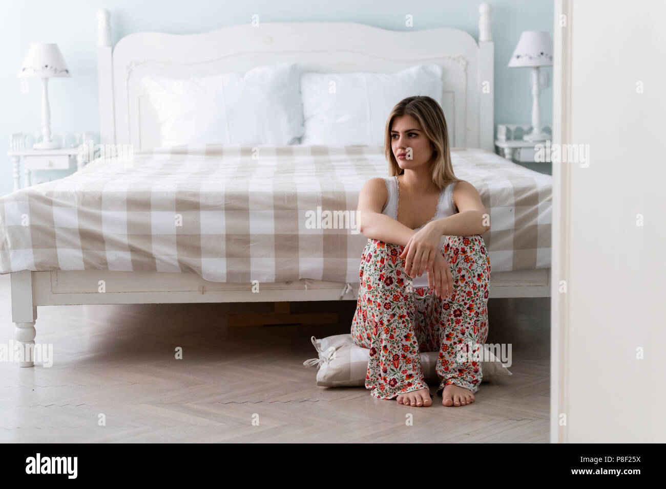 Giovane bella donna infelice seduto in camera da letto Foto Stock