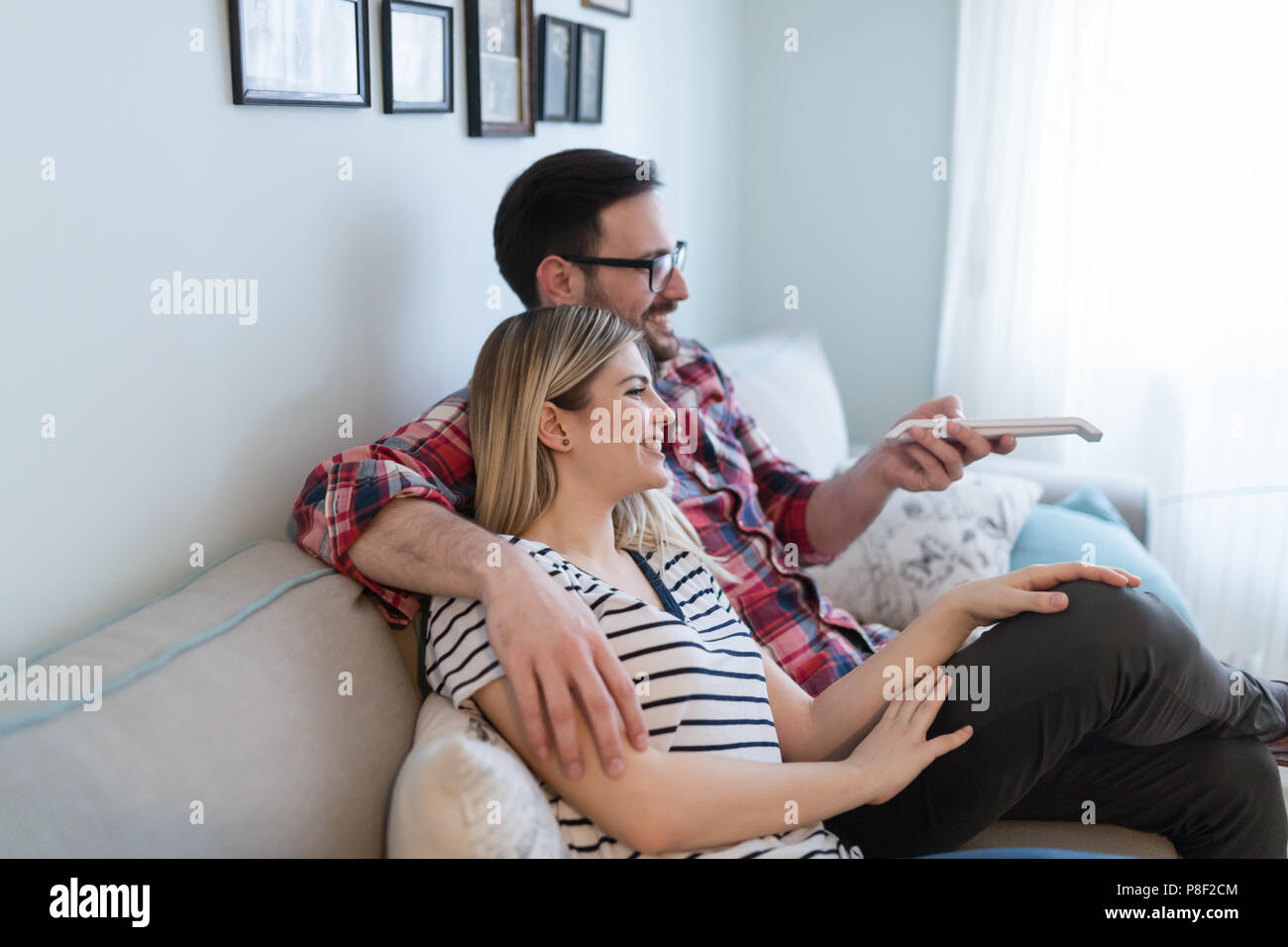 Giovane coppia felice di guardare la tv in soggiorno Foto Stock