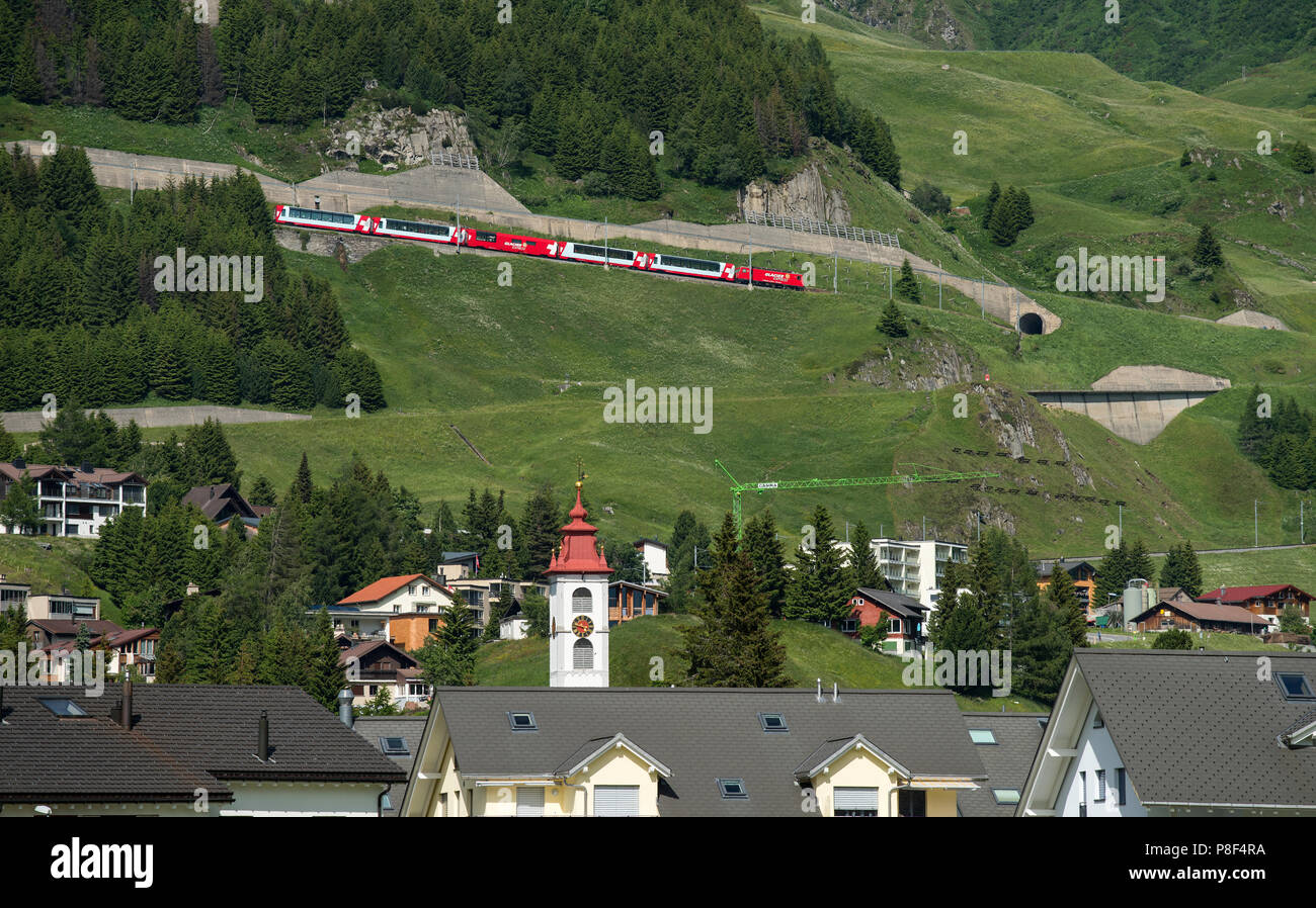 Andermatt nel Cantone di Uri, Svizzera, mostrando Swiss Mountain Trains-Glacier Express- salendo verso Oberalp Pass e Swiss flag. Giugno 2018 Foto Stock