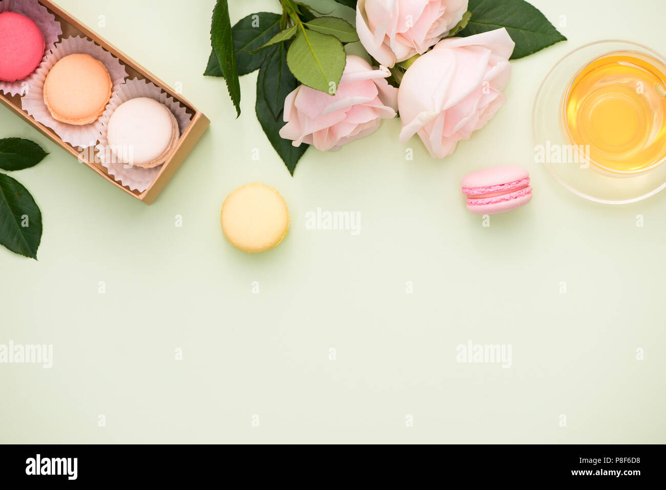 Amaretti colorati e rose fiori con confezione regalo su un tavolo di legno. Dolce macarons in confezione regalo. Vista superiore Foto Stock