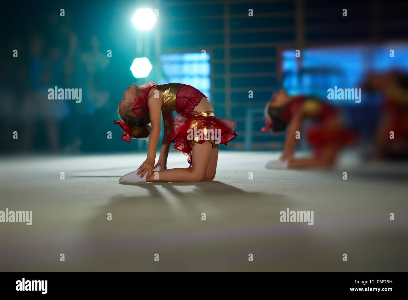 Piccoli ginnasti fare esercizi e sono flessibili, seduto sul pavimento sul palco Foto Stock