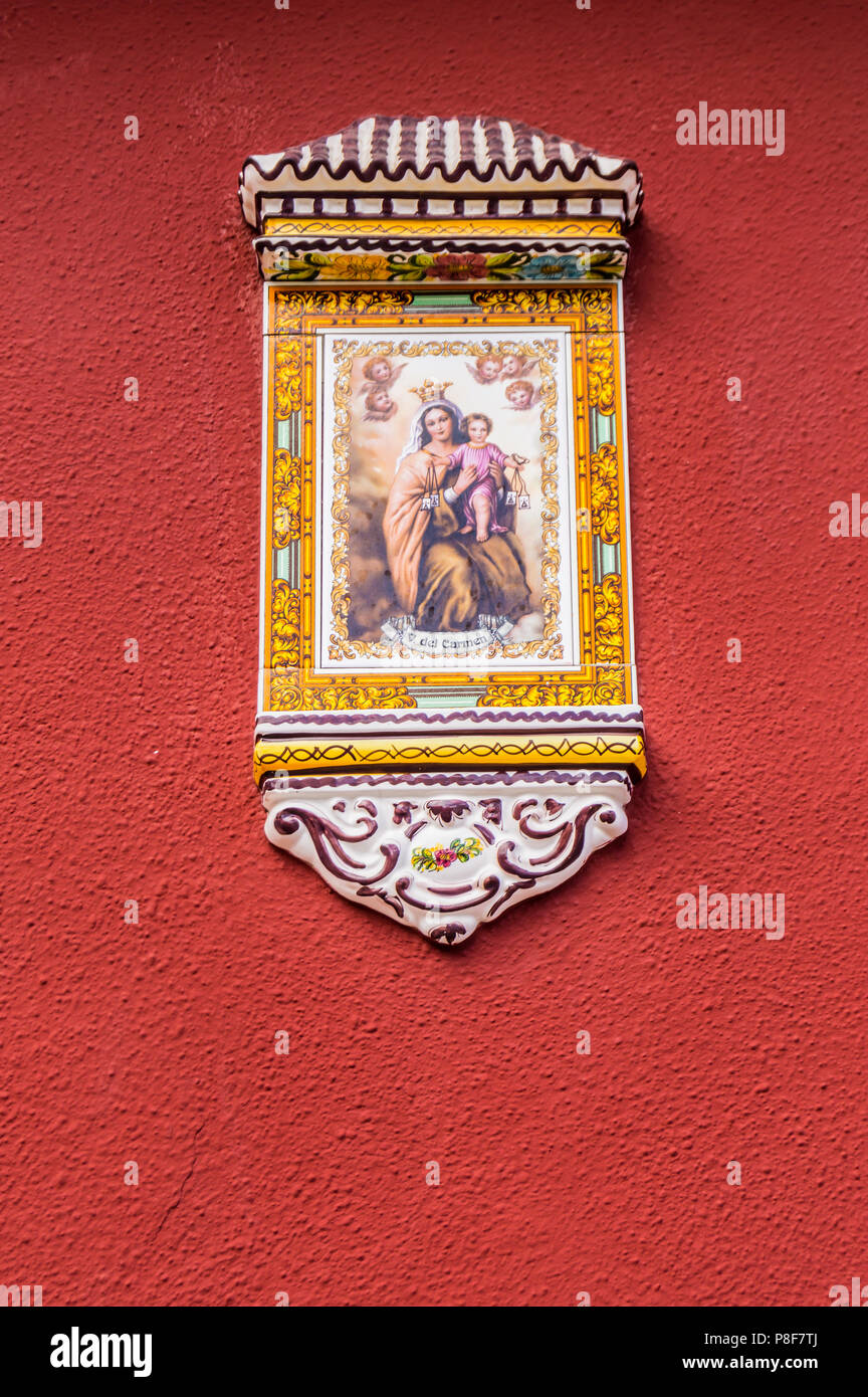 Vergine Maria e Gesù bambino vernici su un piccolo portico di ceramica pongono su un grena parete colorata sull'isola di Tenerife Foto Stock