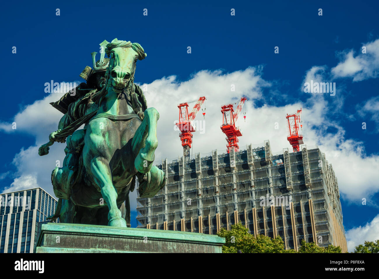 Costruzione di Giappone tra tradizione e modernità. Un moderno grattacielo è in costruzione dietro un vecchio guerriero samurai statua nel centro della citta'. Foto Stock