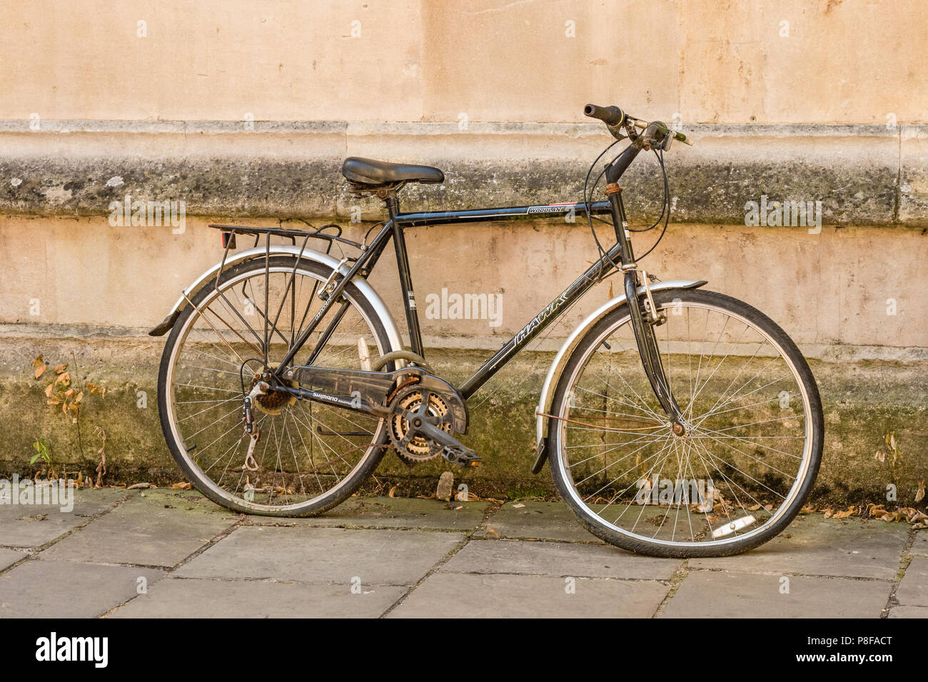 Bicicletta con una ruota piegata che giace contro un muro nel centro di Oxford Foto Stock