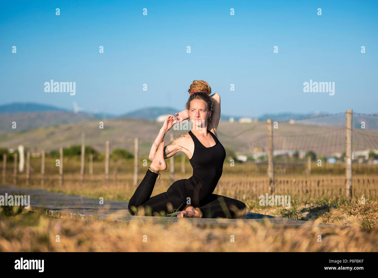 Donna facendo un po' di yoga metà pigeon pongono, lo stretto parco naturale, Tarifa, Cadice, Andalusia, Spagna Foto Stock
