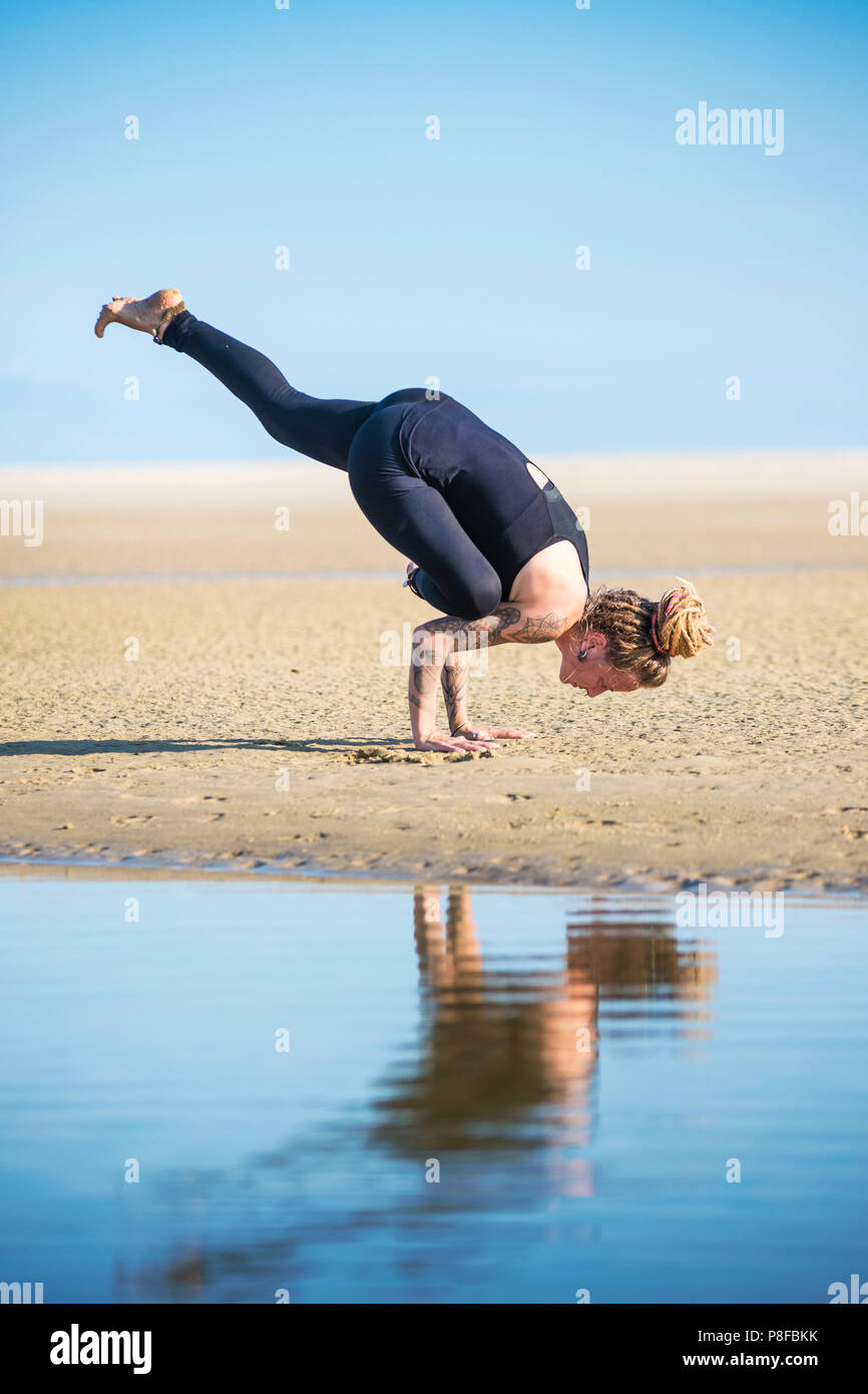 Donna facendo una metà sollevato crow Yoga posa, lo stretto parco naturale, Tarifa, Cadice, Andalusia, Spagna Foto Stock