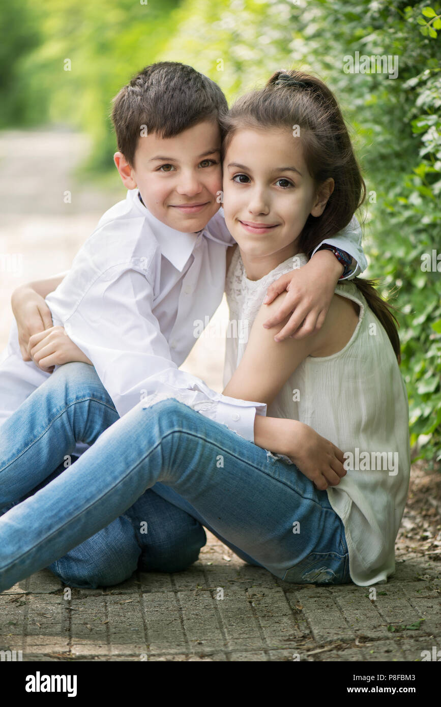 Ritratto di un fratello e una sorella seduti in giardino avvolgente, Bulgaria Foto Stock