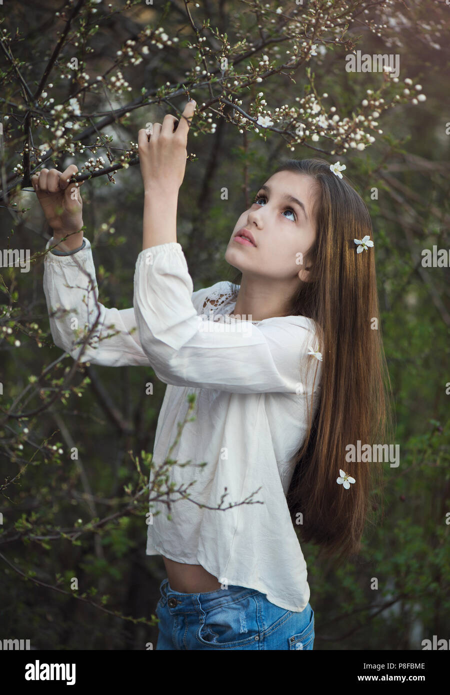 Ritratto di una ragazza in piedi in un giardino tenuta su di un ramo, Bulgaria Foto Stock