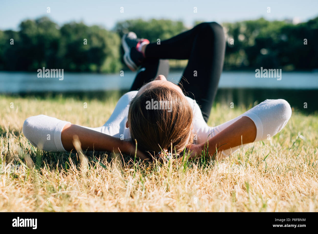 Donna sdraiata sul prato di un parco rilassante Foto Stock