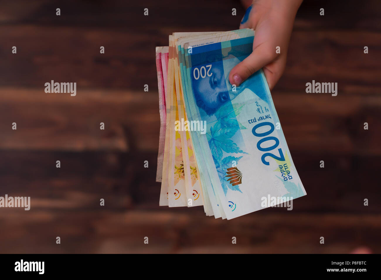 Donna che mantiene un mazzetto di nuovo Israeli Shekel banconote nelle sue mani Foto Stock