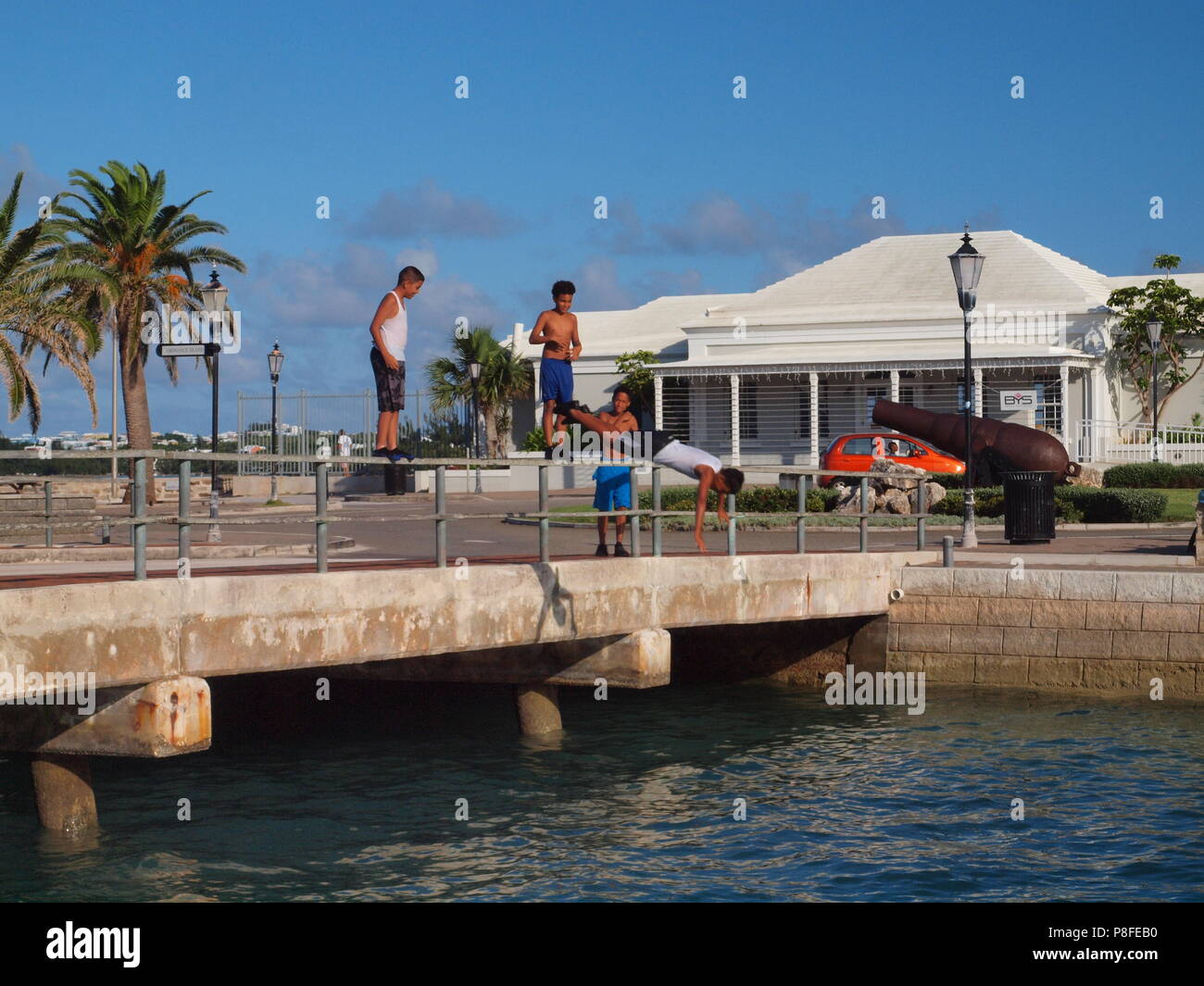 Local Bermudian kids immersioni dalla ringhiera del ponte in acqua vicino Ordnance Isola, Bermuda Foto Stock