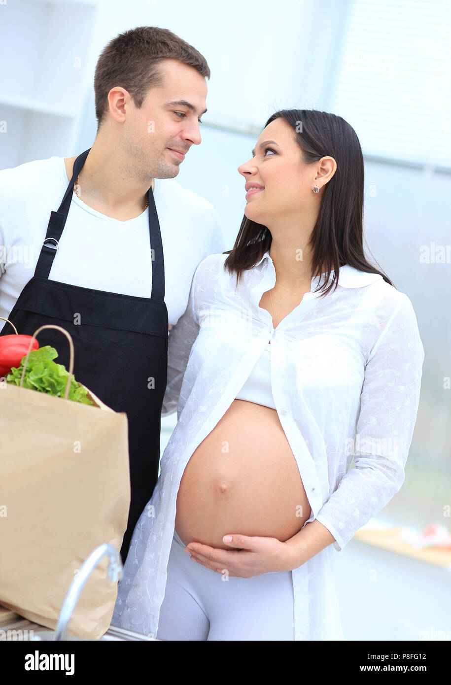 Il marito e la moglie incinta pettinatura sono attraverso il pack,in piedi in cucina Foto Stock