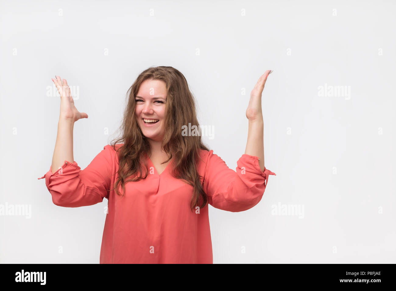 Bella donna in maglietta rossa sorpreso e solleva le mani con sorriso affascinante. Lei ha fatto il suo lavoro e ricevere bonus. Wow è vero concetto Foto Stock