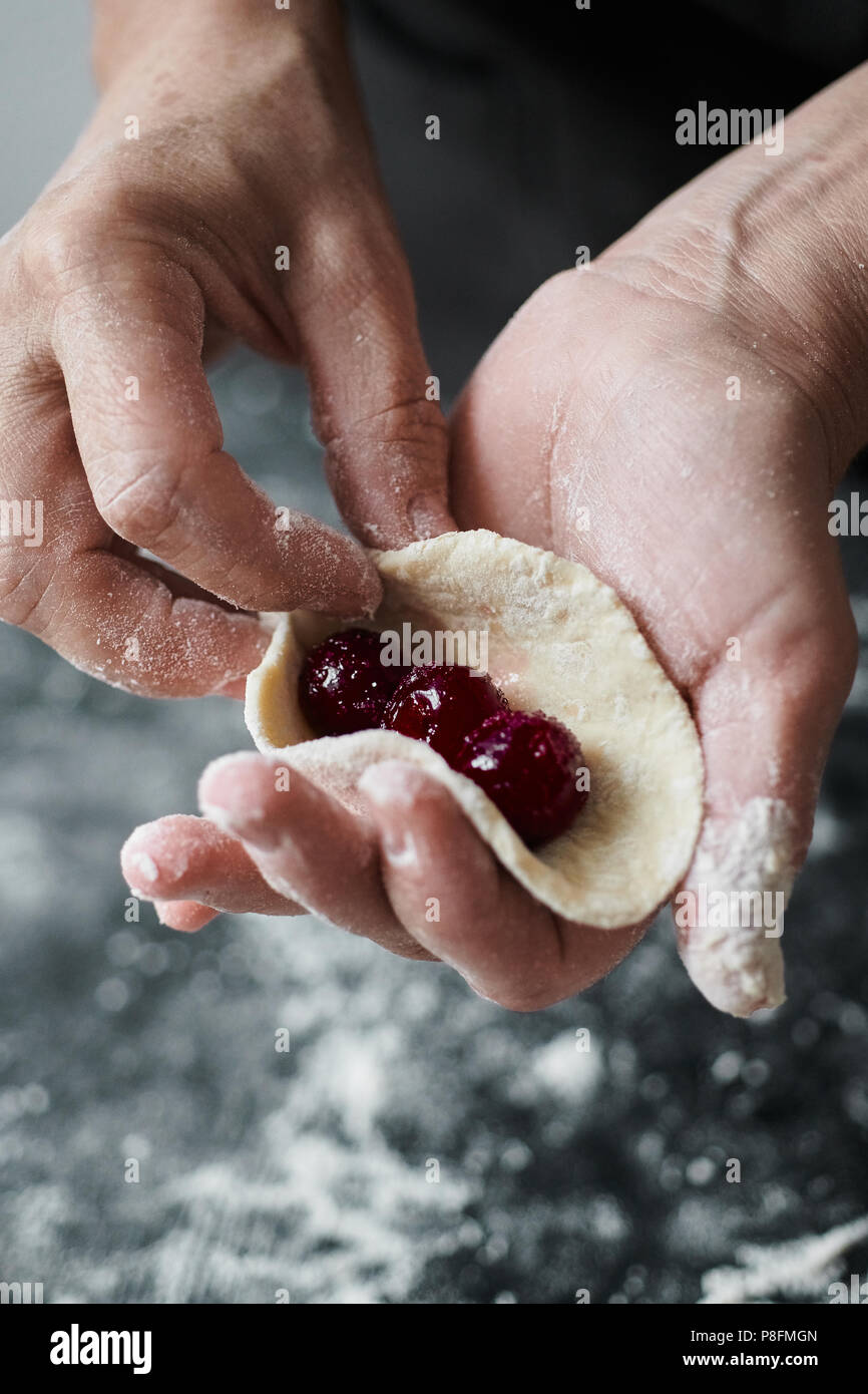 Donna cook scolpisce manualmente ravioli ripieni con ciliegie Foto Stock