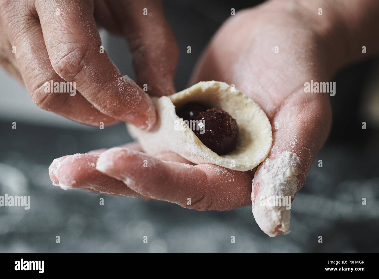 Donna cook scolpisce manualmente ravioli ripieni con ciliegie Foto Stock