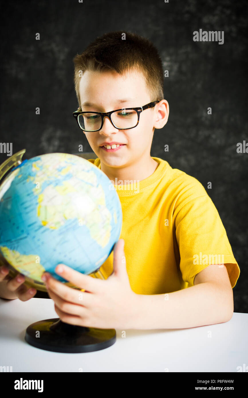 Scolaro ad esplorare il mondo attraverso un globo Foto Stock