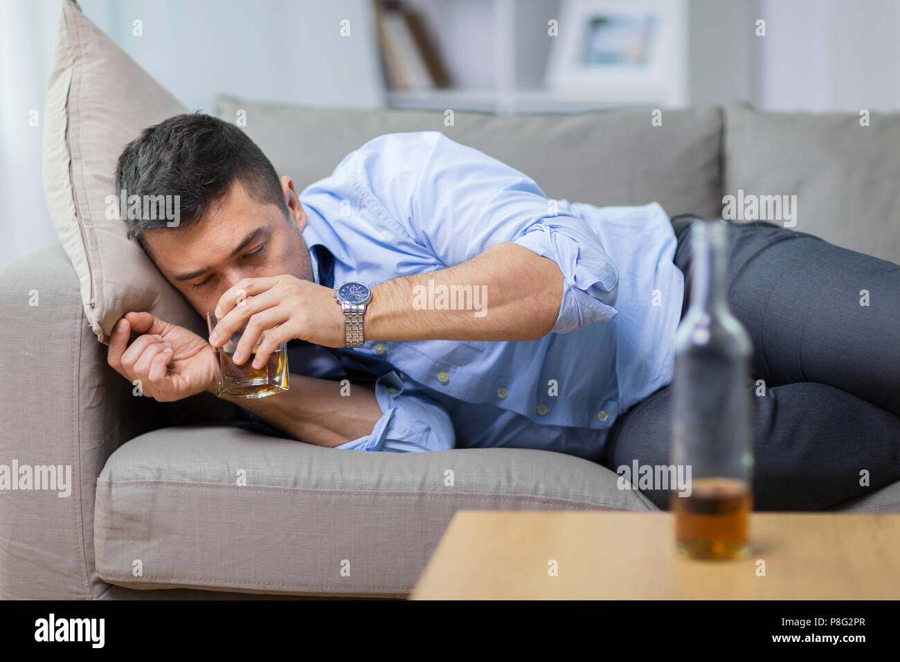 Bevande alcoliche sdraiato sul divano e di bere whisky Foto Stock
