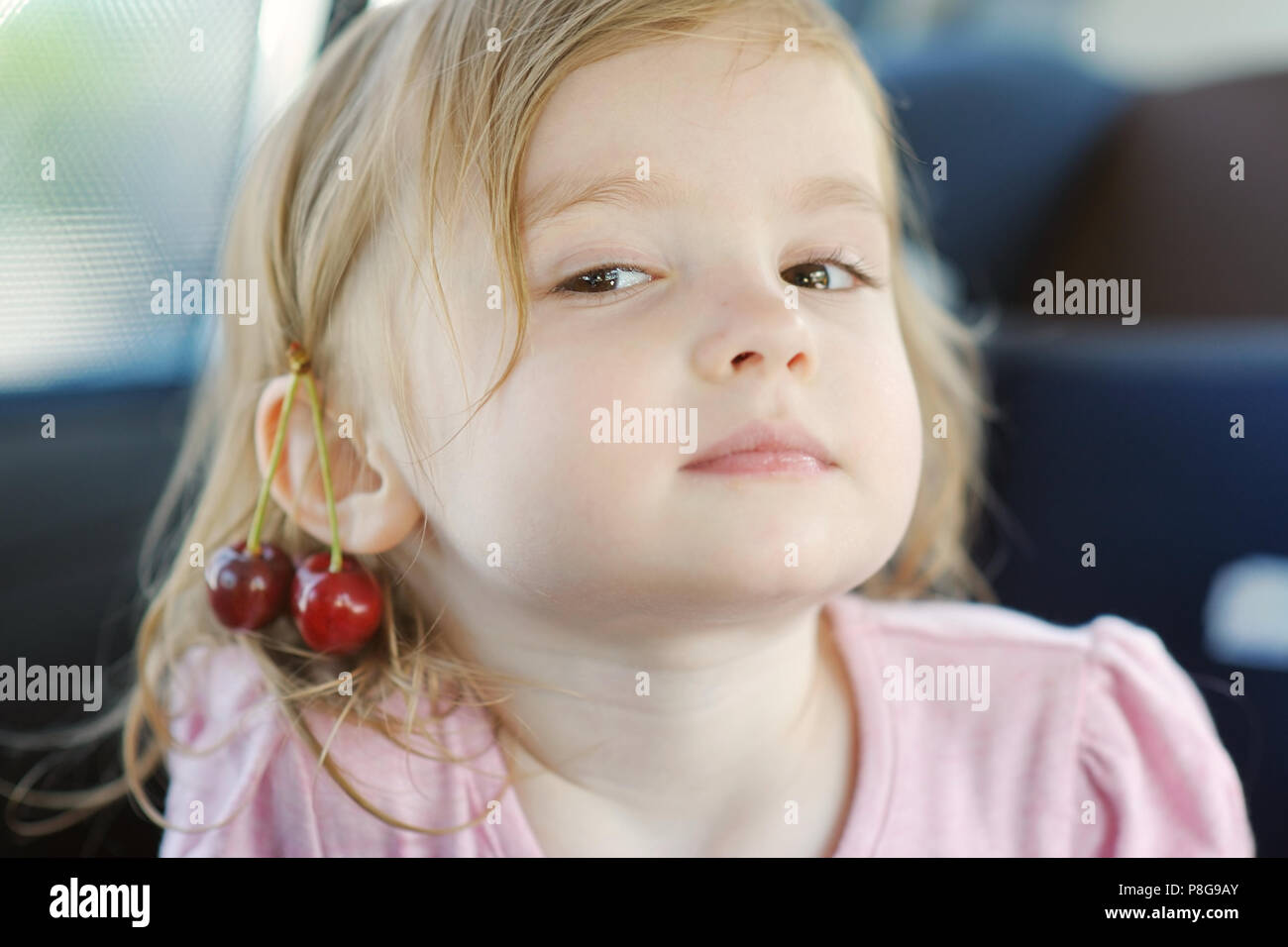 Adorabile bambina con una ciliegia sul suo orecchio Foto Stock