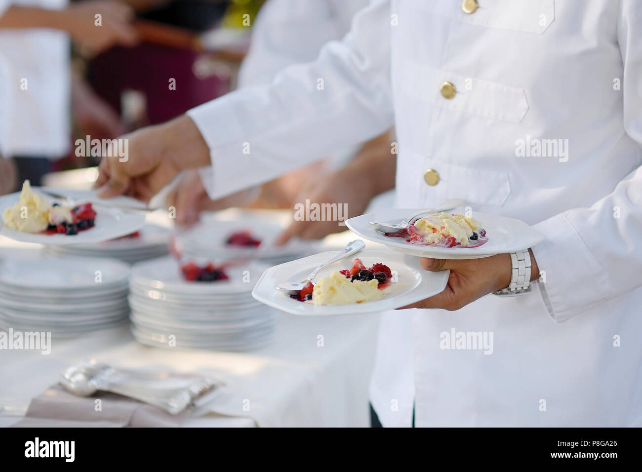 Cameriere che trasportano le tre piastre con dessert Foto Stock