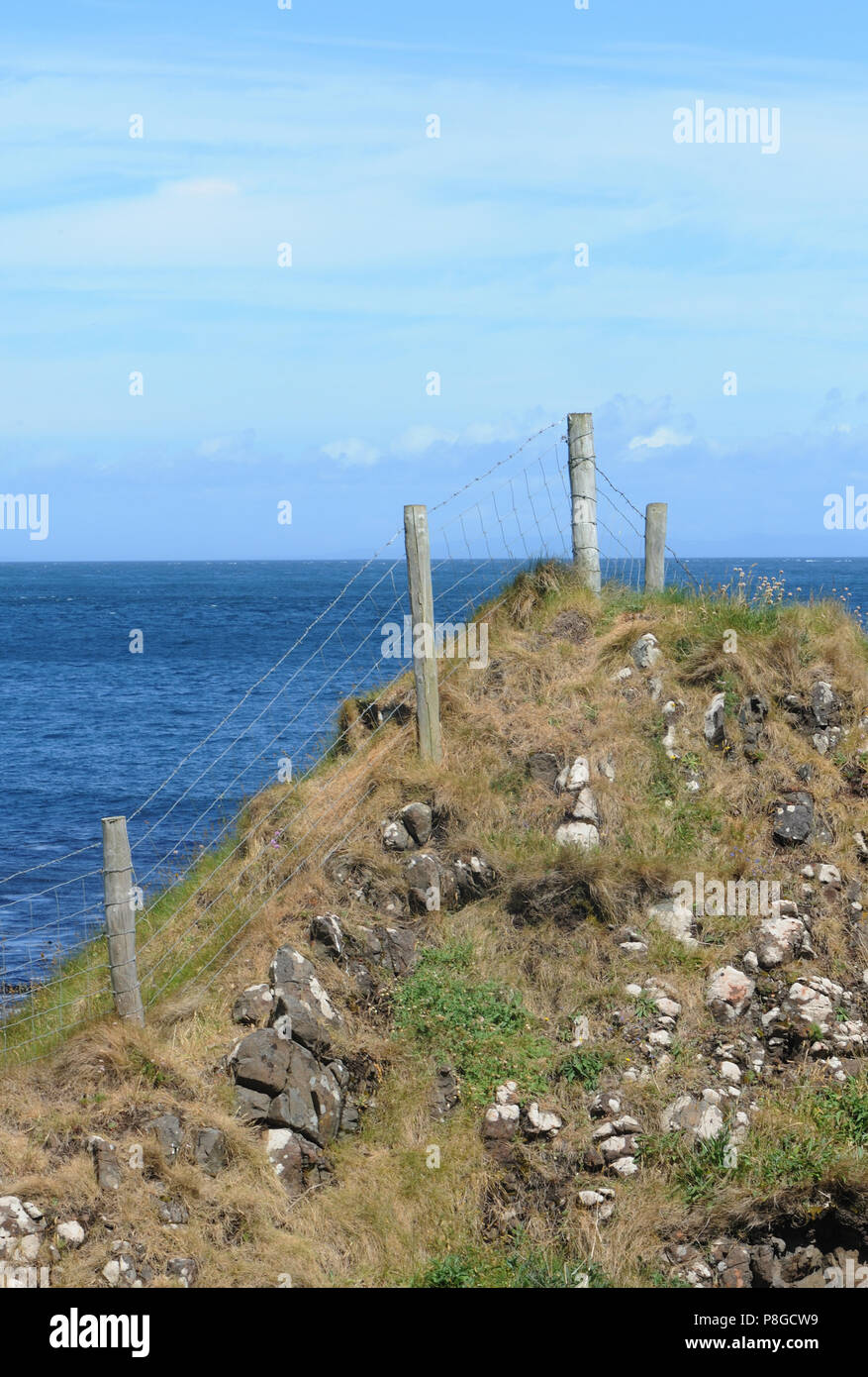 Un recinto di filo corre lungo il bordo di una bassa scogliera. Murlough Bay tra Fair Head e Torr testa. Contea di Antrim, Irlanda del Nord Foto Stock