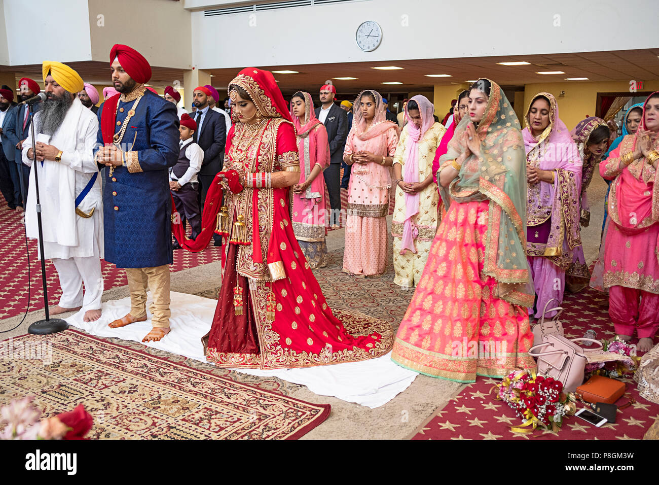 La sposa e lo sposo, sacerdote e gli ospiti di una cerimonia di matrimonio nel tempio presso la società Sikh in Richmond Hill, Queens, a New York City. Foto Stock