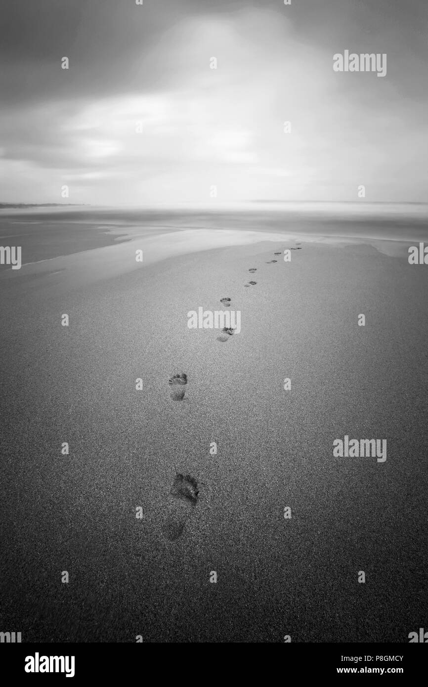 Orme di sabbia su una spiaggia nuvoloso su un triste giorno. Foto Stock