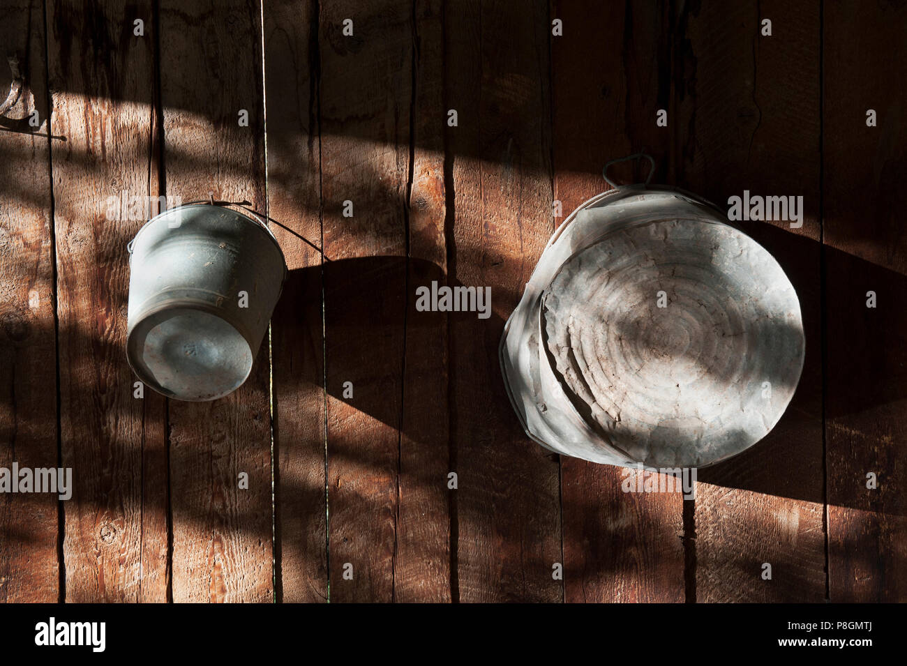 Vecchio cucchiaio di stagno e la vasca di lavaggio appeso su un weathered tavolato in legno parete. Foto Stock