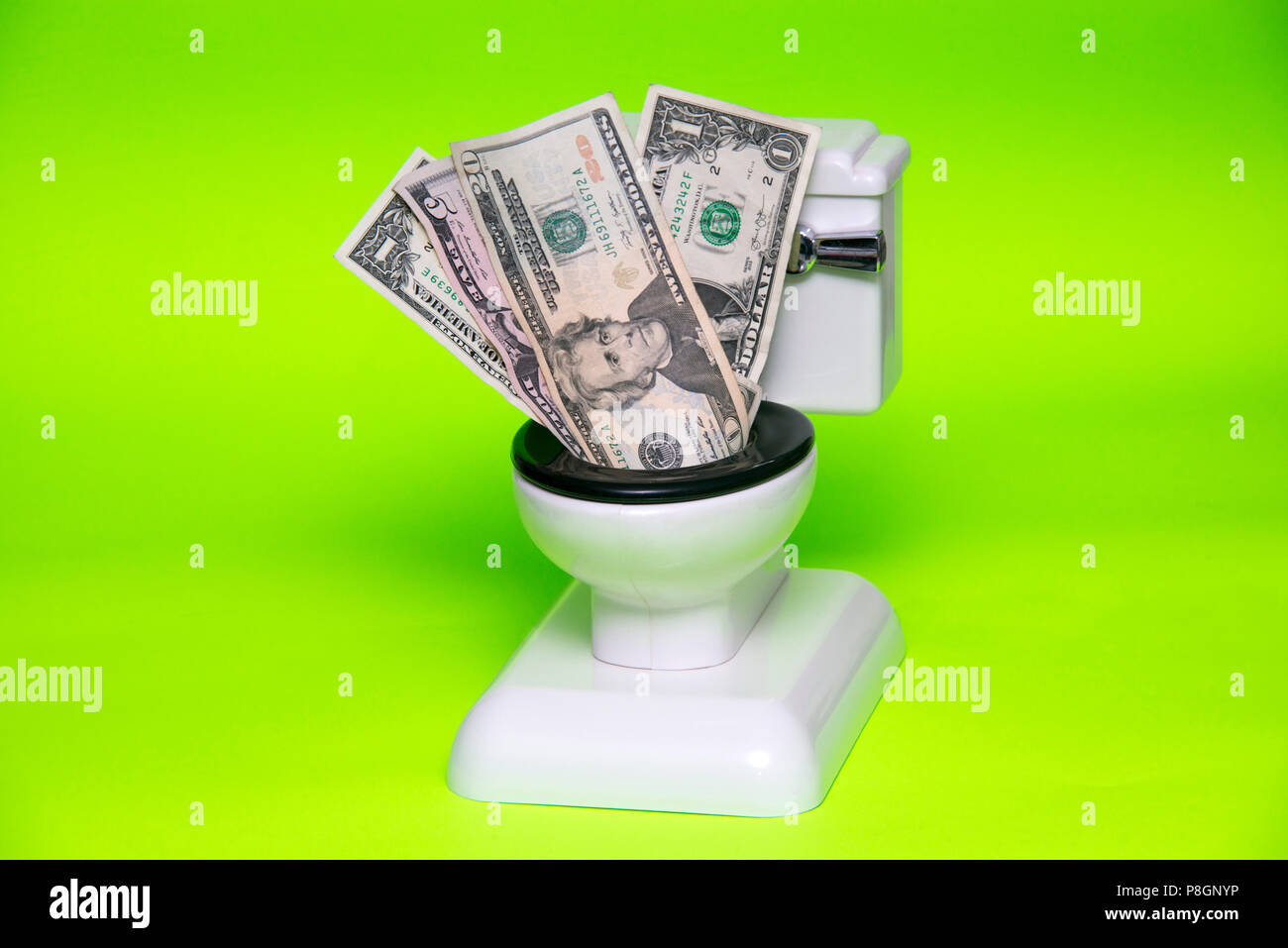 Il denaro che deve essere lavato giù il wc contro lo sfondo di colore verde Foto Stock