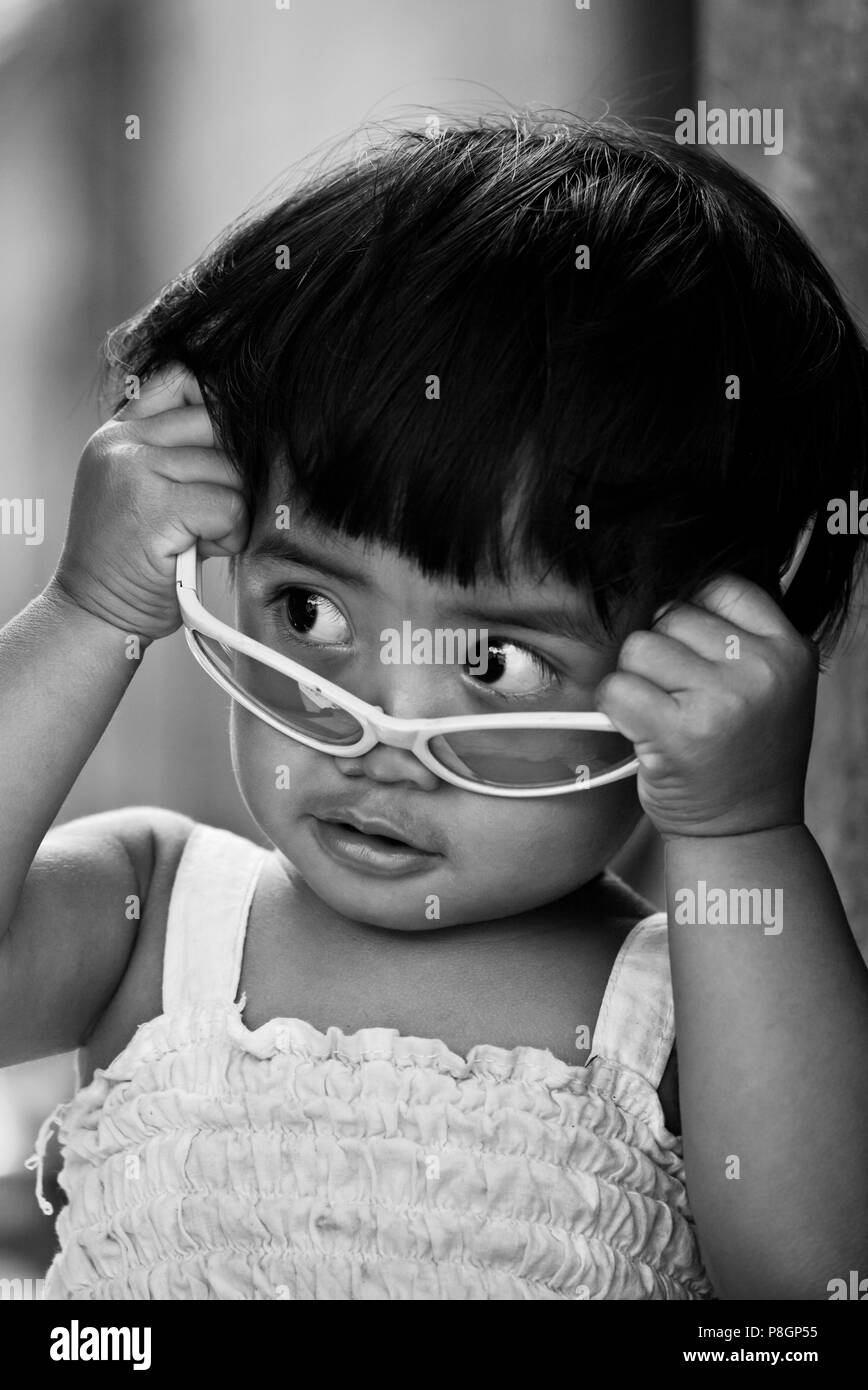 Una ragazza balinese gode la sua SUNGLASSED rosa nel tradizionale villaggio di PENGLIPURAN - Bali, Indonesia Foto Stock