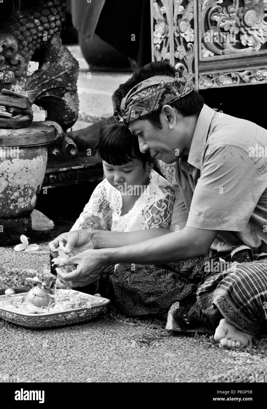 Padre e figlia fare puja alla pura TAMAN SARASWATI durante il GALUNGAN FESTIVAL - Ubud, Bali, Indonesia Foto Stock