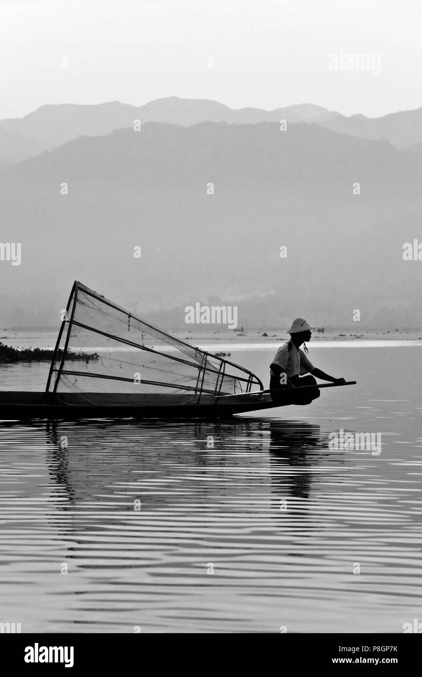 La pesca all'alba viene ancora effettuata in modo tradizionale con piccole imbarcazioni in legno, reti da pesca e gamba canottaggio - Lago Inle, MYANMAR Foto Stock