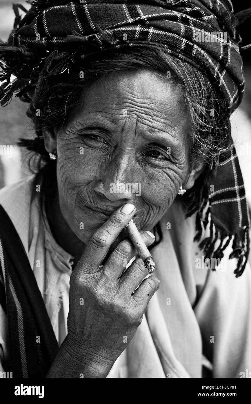 Una donna SHAN fuma un sigaro al mercato YWAMA sul modo di INDEIN - Lago Inle, MYANMAR Foto Stock