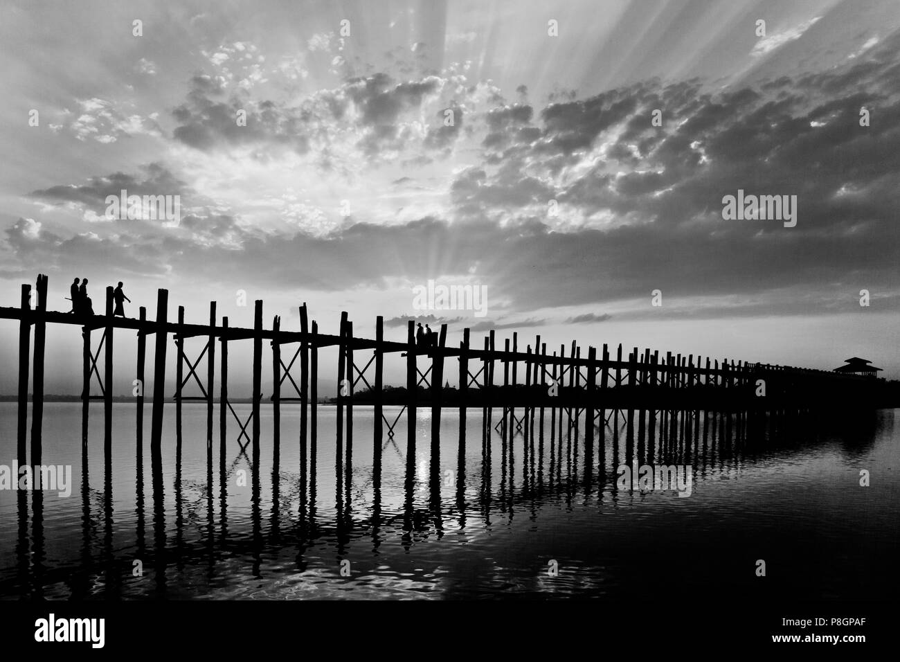 Il birmano utilizzare il teak U BEINS ponte per commutare tra il Lago Taungthaman presso sunrise - AMARAPURA, MYANMAR Foto Stock
