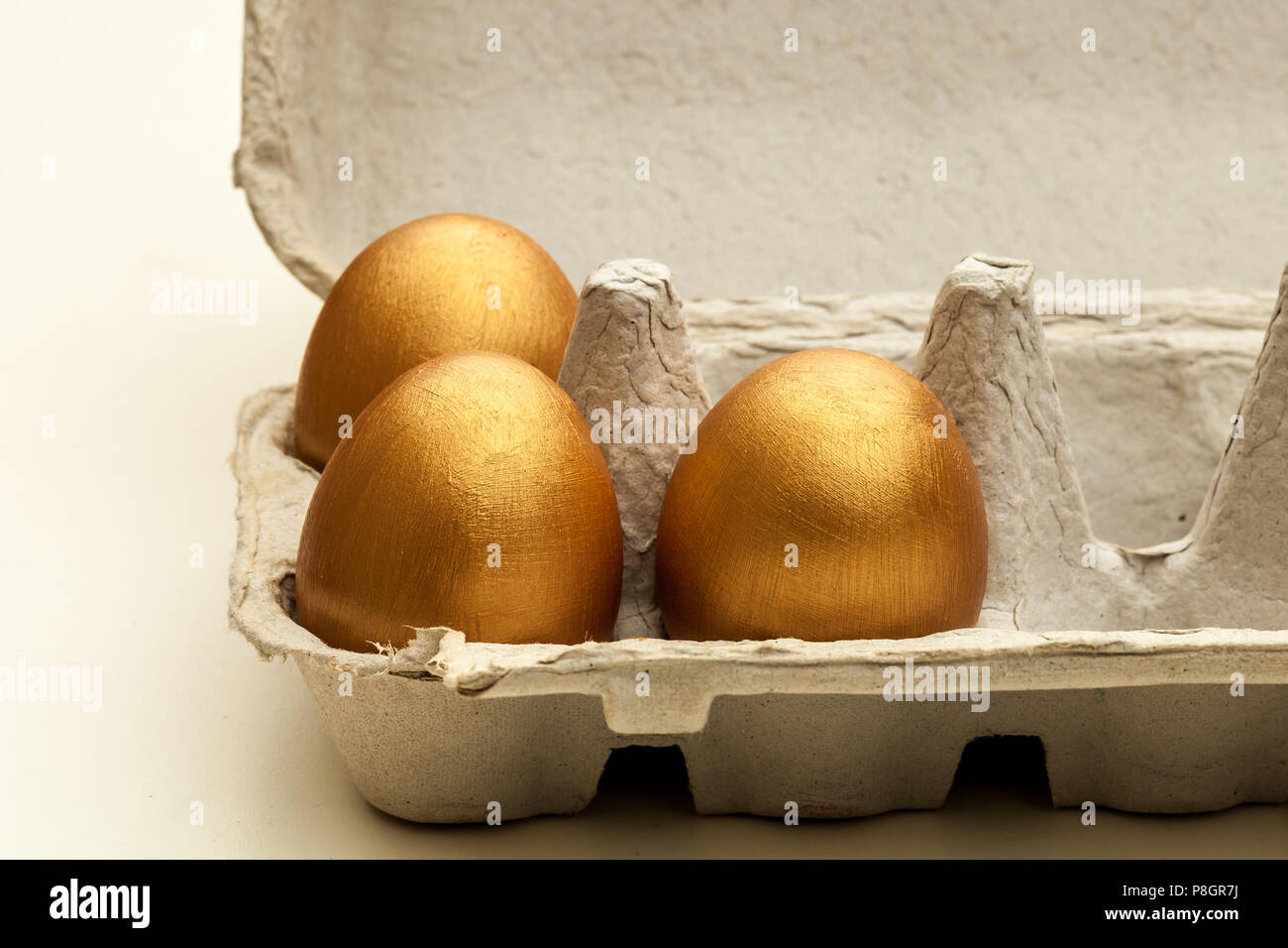 Dipinte a mano uova d'oro in una confezione di uova Foto Stock