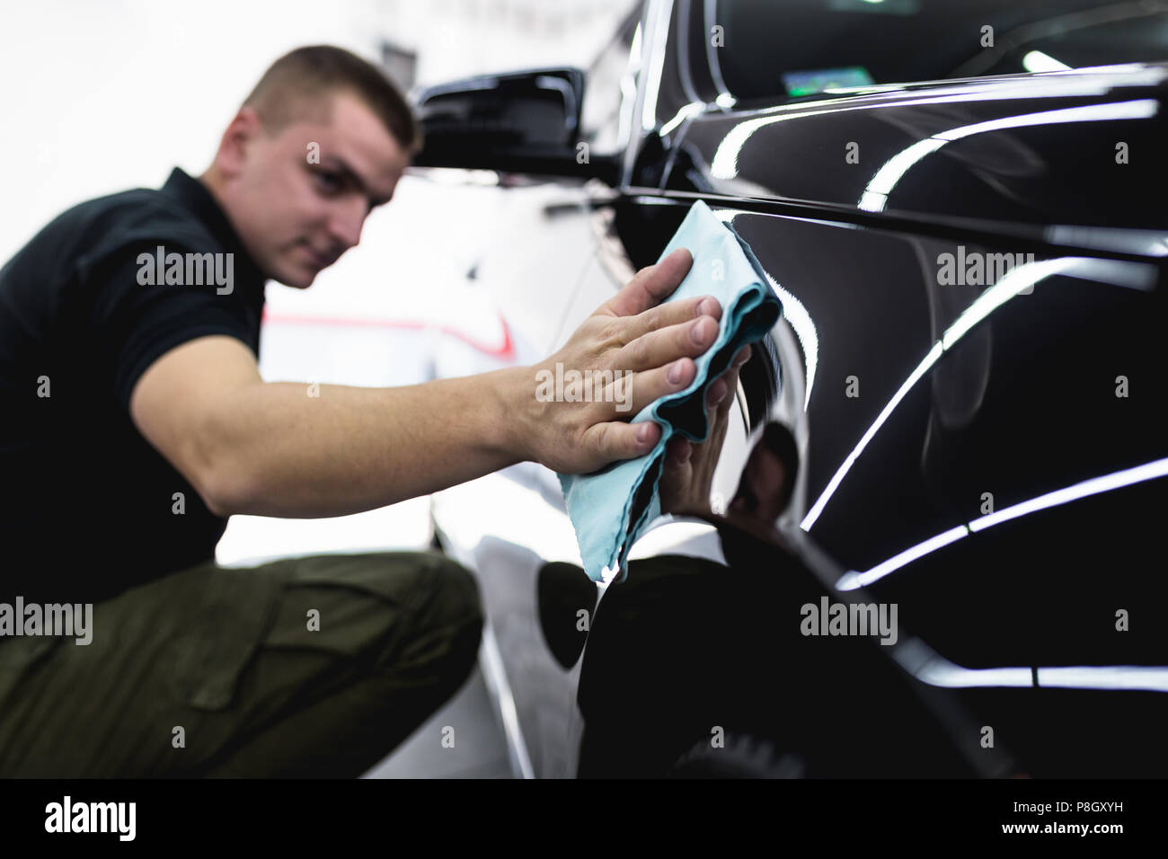 Un uomo che pulisce auto con panno in microfibra, auto che dettaglia (o valeting) concetto. Foto Stock