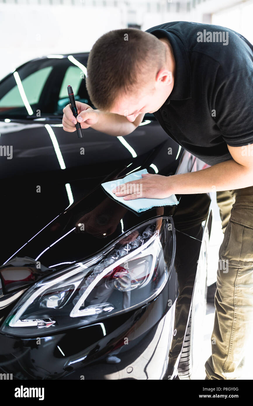 Un uomo che pulisce auto con panno in microfibra, auto che dettaglia (o valeting) concetto. Foto Stock