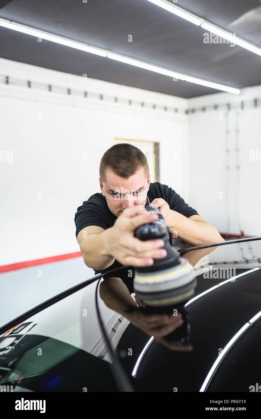 Dettagli auto - Lavoratore con lucidatrice orbitale nel negozio di riparazioni auto. Foto Stock