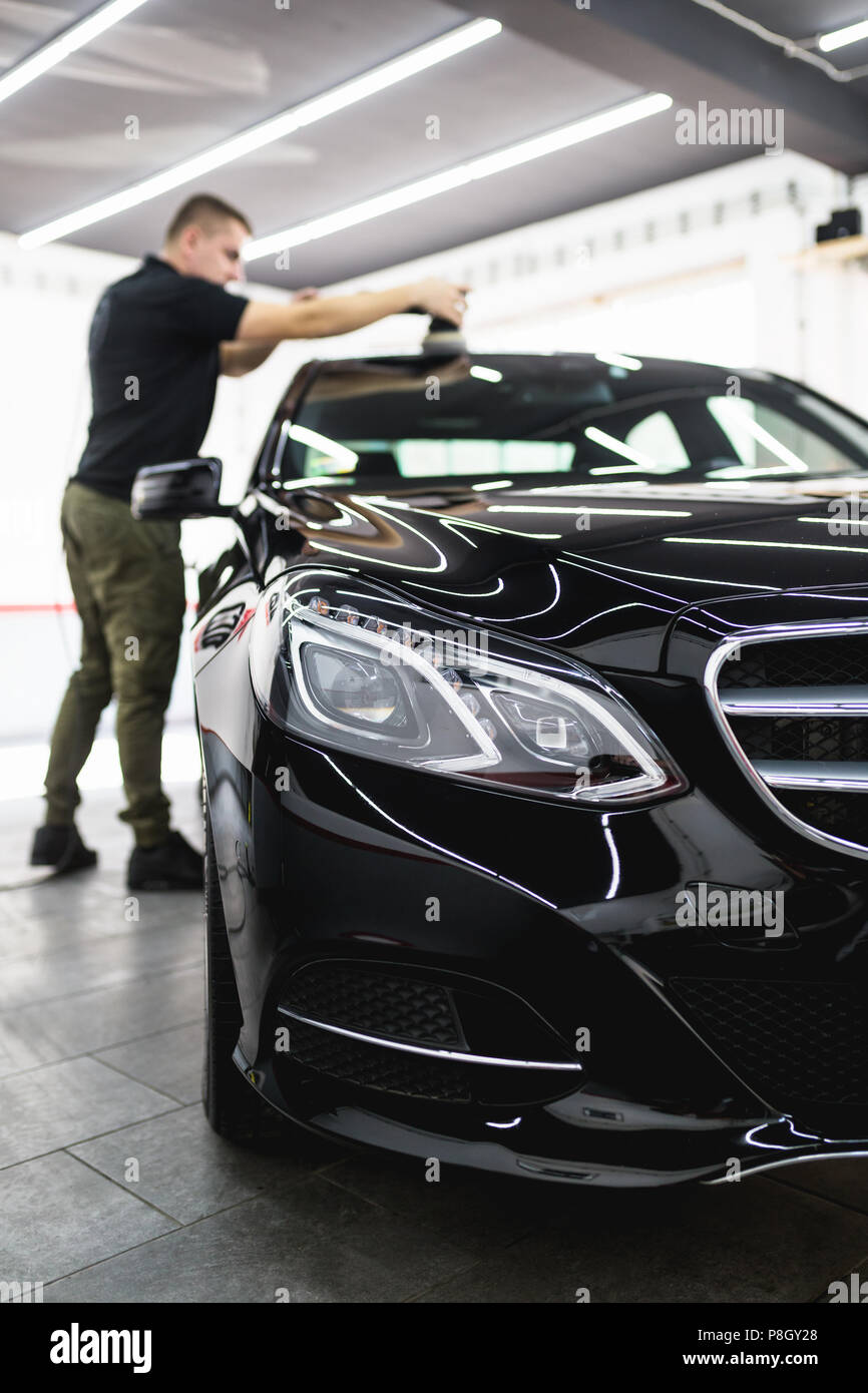 Dettagli auto - Lavoratore con lucidatrice orbitale nel negozio di riparazioni auto. Foto Stock