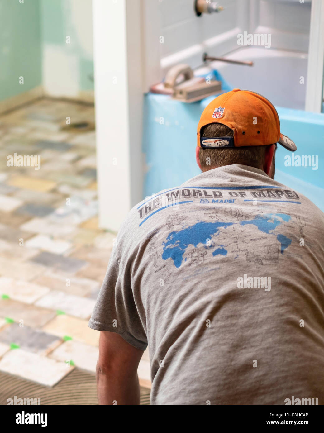 A 40 anno vecchio uomo caucasico posa elegante mattone sottile decorazione piastrelle del pavimento in un bagno durante un rimodellamento home lavoro in Wichita, Kansas, Stati Uniti d'America. Foto Stock