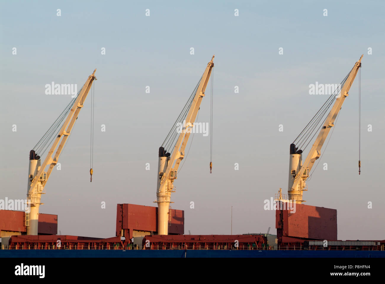 Drei Kraene auf einem Frachter im Hamburger Hafen, synchron ausgerichtet. © Martin Langer/Agentur FOCUS Foto Stock