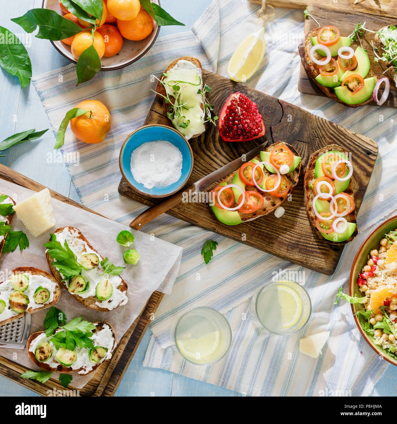 Set di piatti vegetariani su blu tavolo in legno con limonata fatta in casa. Bruschetta con pomodori, cetrioli, cavolini di Bruxelles e insalata con ceci una Foto Stock